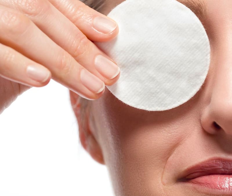 Close-up of woman removing eye make-up using cotton pad